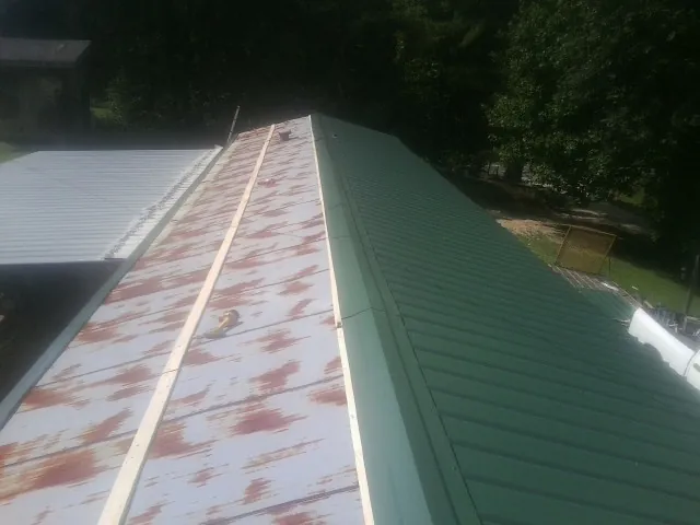 Old rusted panels beside newly installed green metal roofing — Wind Damage Roof Repair by Roofing Brothers in Hopkinton