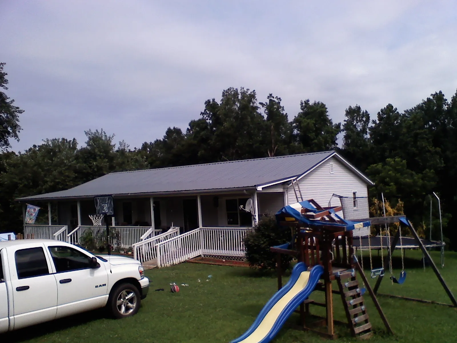 Dark metal roof on a country home with a full length front porch in Hopkinton