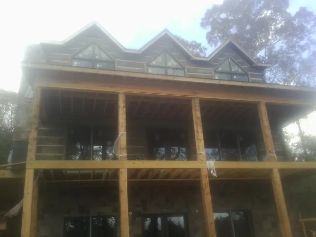 Dormers and porch framing on a large log home under construction — Roof Coating work by our crew in Hopkinton
