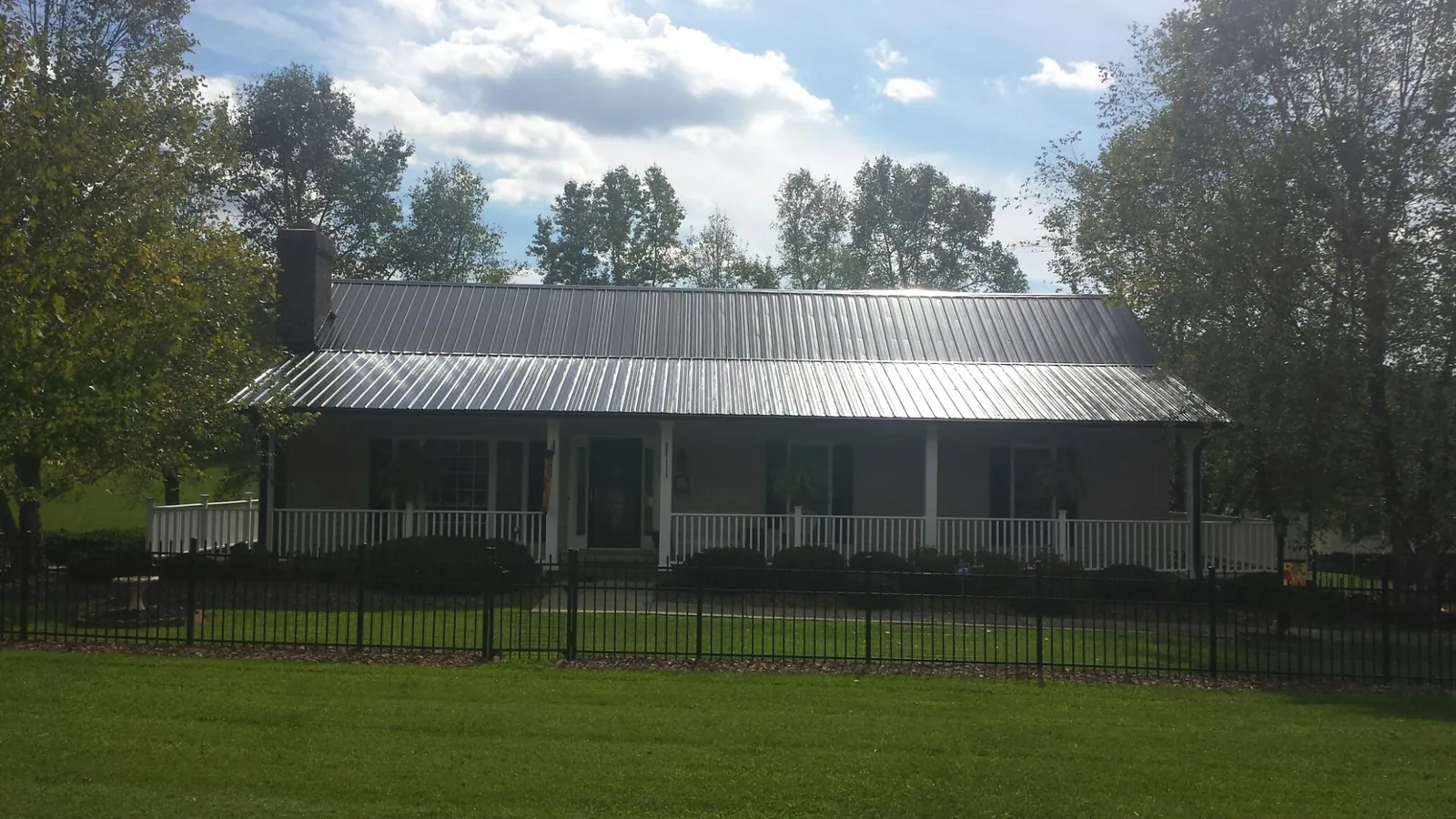 Gray metal roof on a brick ranch with a full width front porch — Gutter Guard Installation work by our crew in Hopkinton